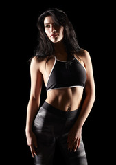 Fototapeta na wymiar Portrait of a young brunette sporty fitness woman on black