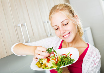 Woman serving salad on kitchen