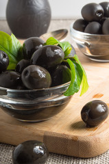 Black olives in a glass bowl decorated with green leaves