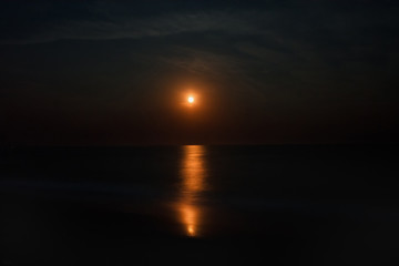Night seascape with a red moon and a moonlight path