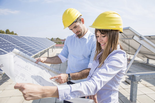 Two architects with blueprint at solar power station