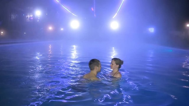couple man and woman swimming in a pool with thermal water at night.