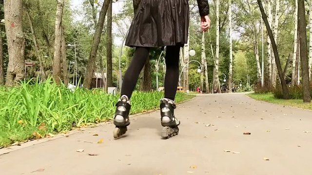 Rollerblading. Dark-haired stylish woman moving on rollerblades. The view from the back. Slow motion. HD