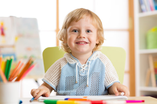 cute child little boy drawing with felt-tip pen in kindergarten classroom
