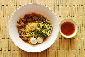 Chinese egg noodle topping braised pork in brown soup and spicy chili sauce