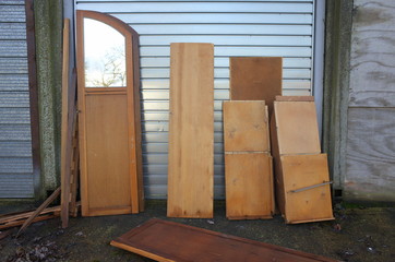 Dismantled and discarded wooden wardrobe or cabinet dumped in front of a garage or storage space