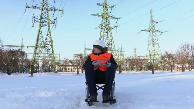 Disabled worker on wheelchair using tablet near to high-voltage lines