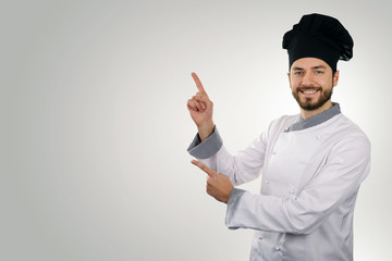 young happy chef pointing on copy space