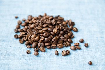Brown roasted coffee beans on natural linen fabric background.
