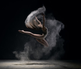 Fototapeta na wymiar Girl in body jumps in dust cloud black background