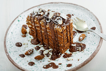 Slice of delicious chocolate Spartak cake on a rustic plate. First class dessert on a white wooden table.