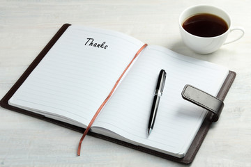 The word Thank you written in a notebook lying on the table.