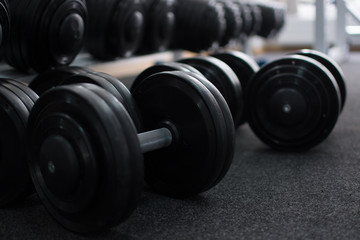 Rows of dumbbells in the gym in the dark colors.