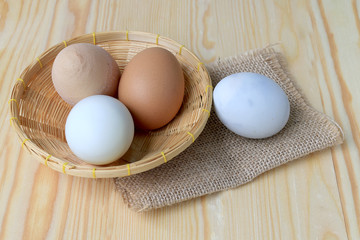 Chicken eggs and duck eggs in basket on a wooden table background.