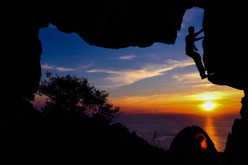 Camping and rock climbing in the cave on the mountain with red sky sunset. 
