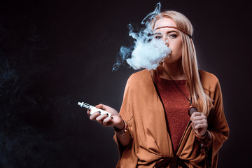 Young woman in the Boho style blowing smoke