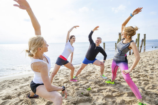 Group of friends stretching on beach