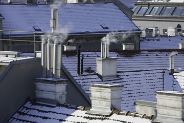 Rauchende Schornsteine im Winter mit Schnee auf Dächern