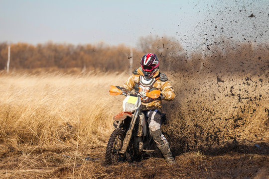 Enduro bike rider on a field with dry grass in autumn. The motor