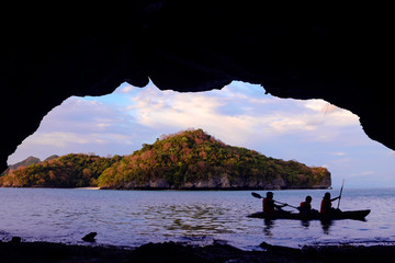 Family paddling a kayak through the cave by the sea. 