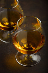 Glass of brandy or cognac on the old rusty background, selective focus, vertical, 