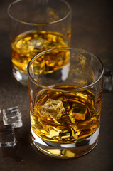 Glass of whiskey with ice on the old rusty background, selective focus, vertical