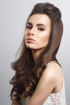 Beauty portrait of a brown-haired sexy girl with elegant hair isolated on gray background.