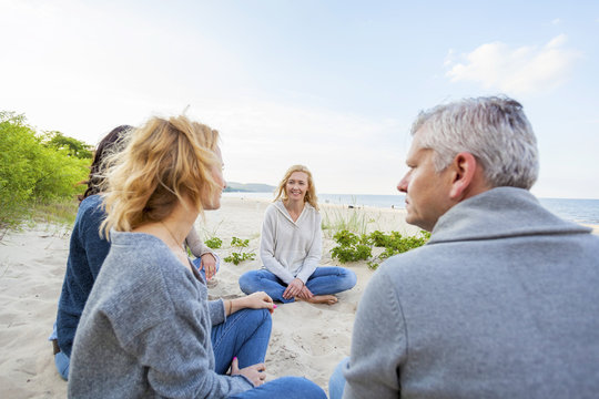 Group of friends sitting on sandy beach