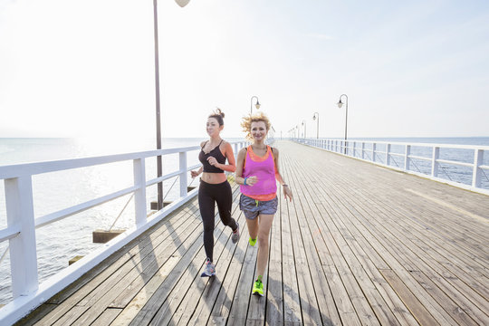 Two Women Jogging Along A Jetty