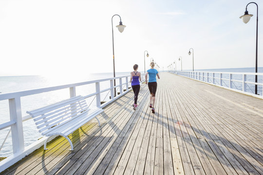 Two women jogging along a jetty