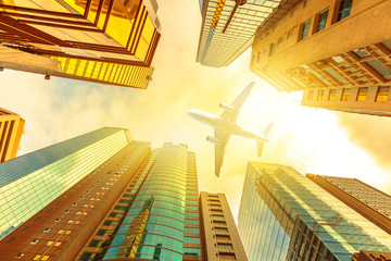 Airplane flying over modern skyscrapers on Hong Kong, Central District with sun light of sunset...