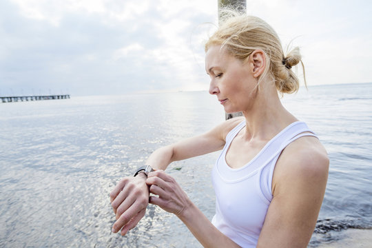 Woman on beach checking running watch