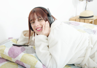 beautiful young girl listening to music in her bed