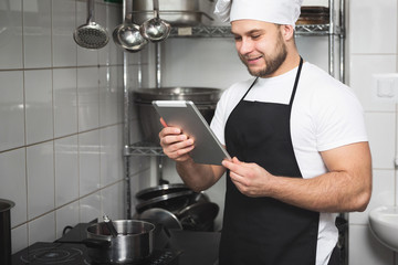 Smiling chef reading on tablet