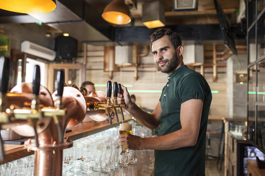 Bartender in coffee shop pouring beer from tap
