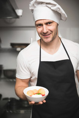 Confident male chef holding bowl with dessert