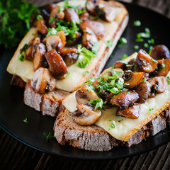 Rustikaler Snack: Frisches Brot mit Raclette Käse, Pilzen und frischen Kräutern