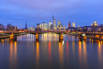 Fototapeta na wymiar Picturesque view of Frankfurt am Main skyline and Ignatz Bubis Brucke bridge during evening blue hour with mirror reflections in the river, Germany