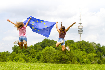 Two women jumping while holding European flag