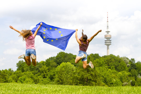 Two women jumping while holding European flag