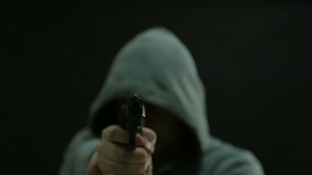 Man in green hoodie points gun and fires