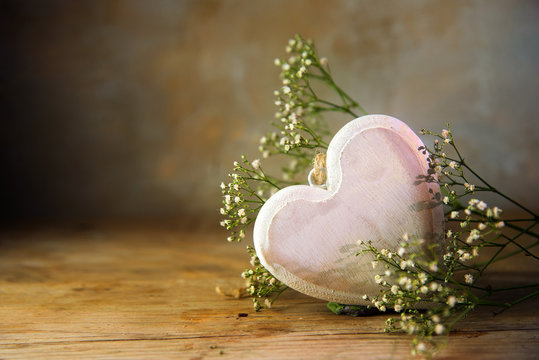 Bright pink heart from wood and white flowers against a warm  vintage background