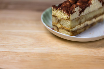Sliced Tiramisu cake on dish on wooden background