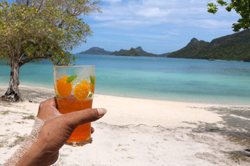 Glass of orange juice on the beach with views of the archipelago Islands 