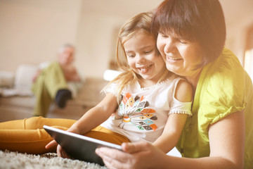 Grandmother and granddaughter using tablet.