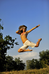 Happy woman jumping on summer time. She is wearing short white pants and bikini. She is holding her...