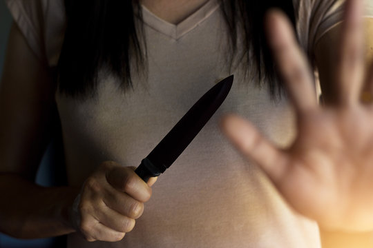  Woman holding a knife in hand while defending herself from attack