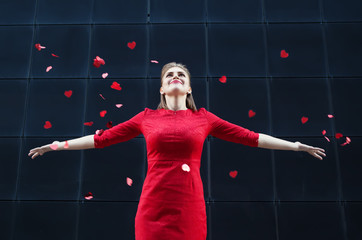 Valentine's Day concept, woman in red dress blowing on a paper heart.