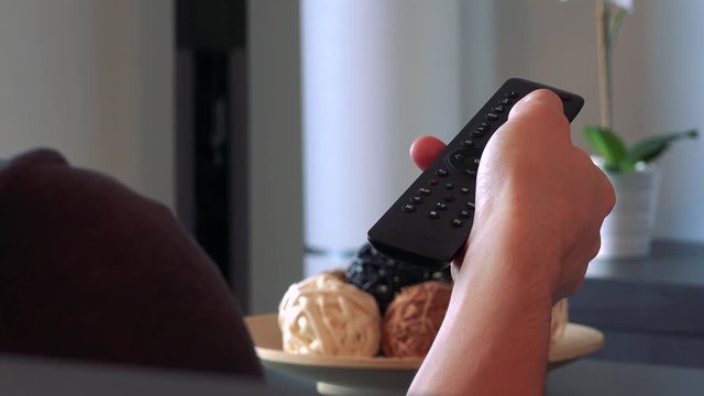 A hand uses a TV controller in living room 