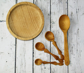 Wooden kitchen spoon and plate on the table, top view